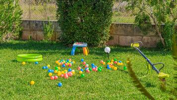 A grassy outdoor area with a trampoline, a small table, and a lawnmower.
