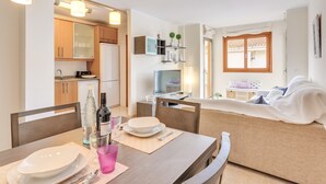 Een moderne keuken met houten kastjes, een eettafel gedekt met borden, een roze glas en flessen.