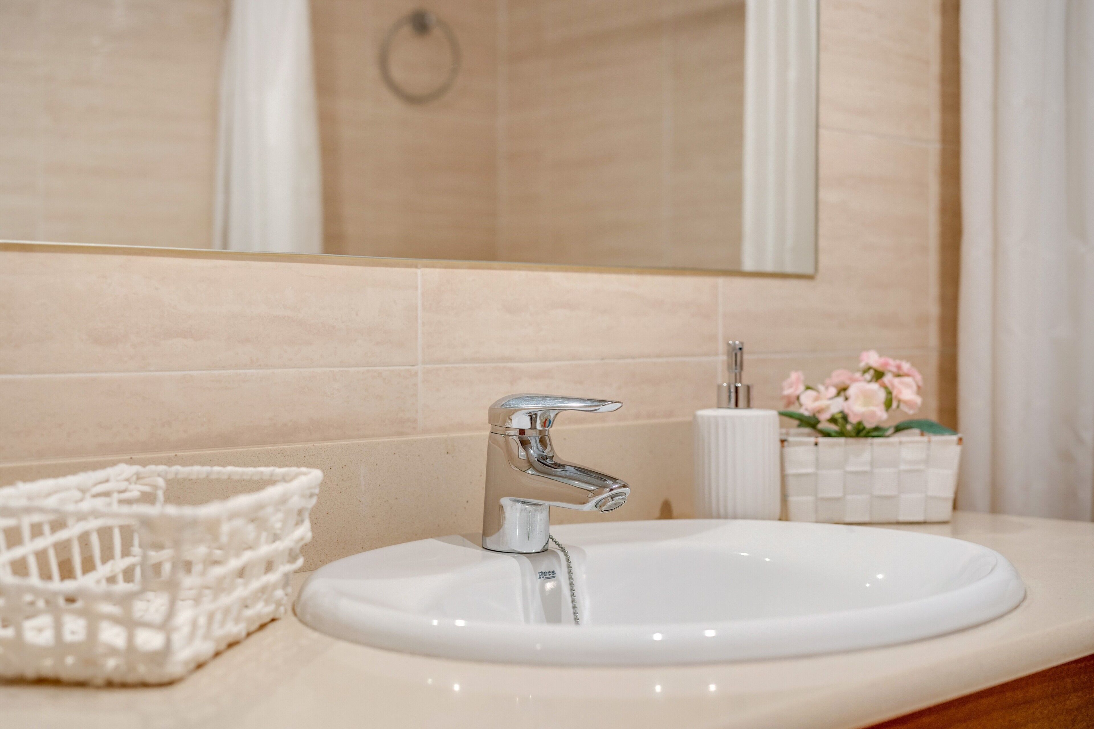 A bathroom with a white sink, chrome faucet, and a mirror above it.