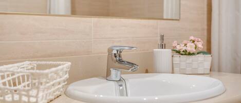 A bathroom with a white sink, chrome faucet, and a mirror above it.