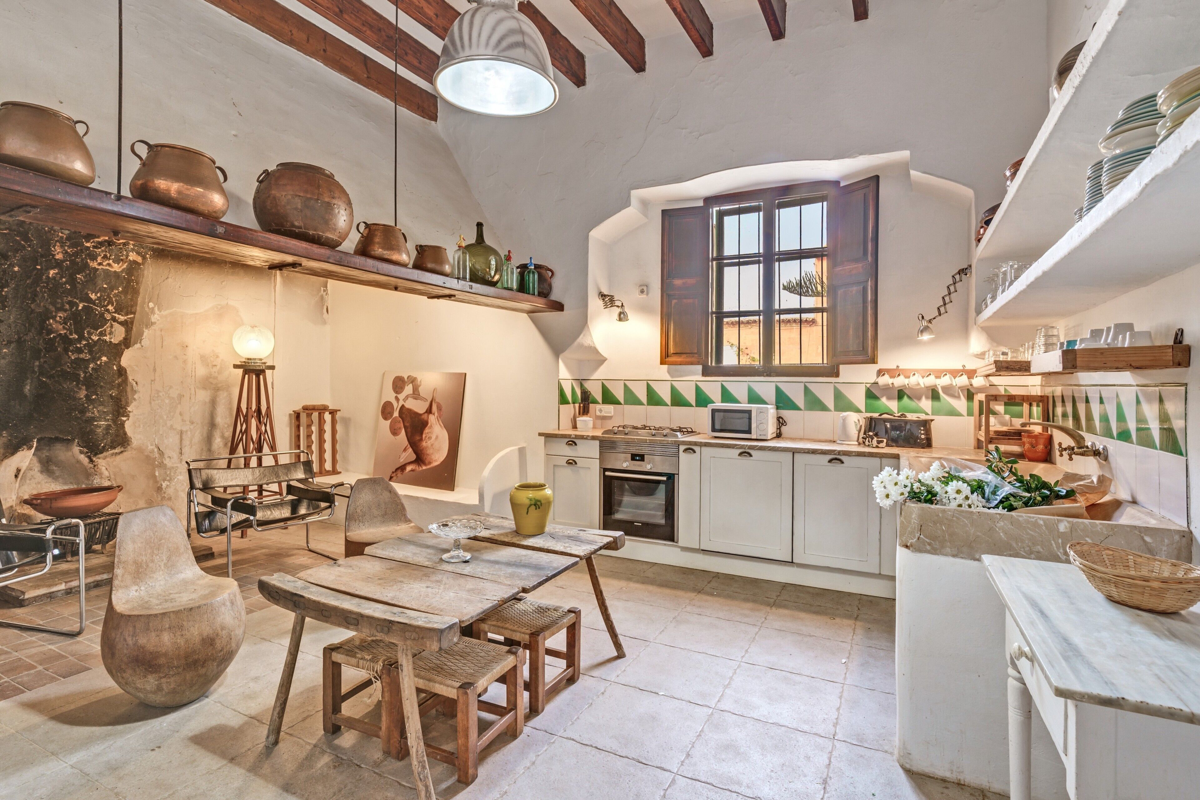 A rustic kitchen with wooden furniture, a dining table, and various kitchen appliances.