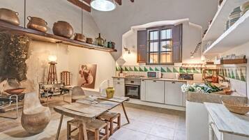 A rustic kitchen with wooden furniture, a dining table, and various kitchen appliances.