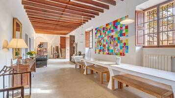 A spacious room with a wooden ceiling, a long white counter, wooden benches, and a colorful abstract painting on the wall.