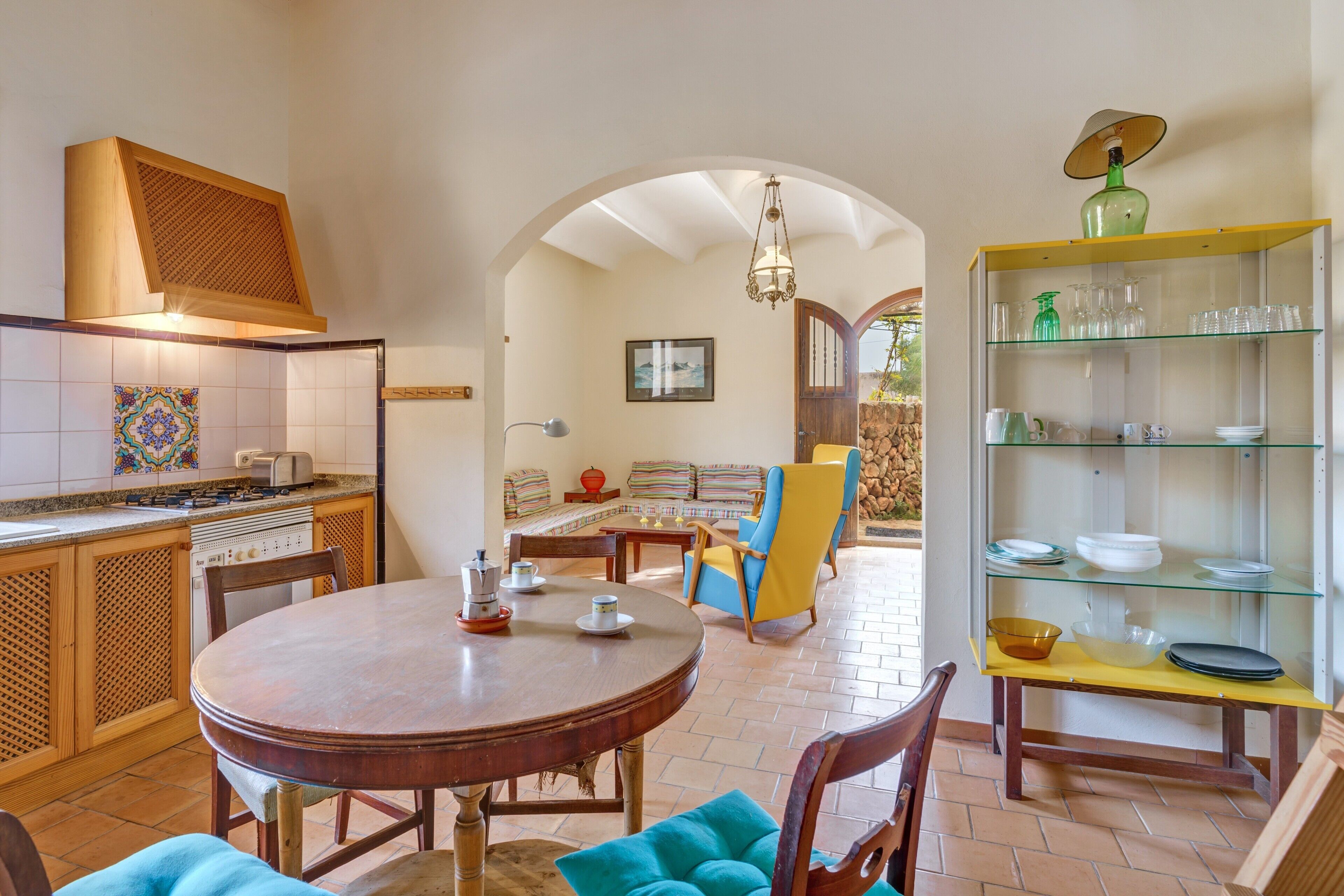 Une cuisine équipée d’une cuisinière, une table à manger avec des chaises et un coin salon avec un canapé et des fauteuils.