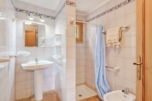 Une salle de bain équipée d’un lavabo, d’un miroir, d’une douche et d’un porte-serviettes.