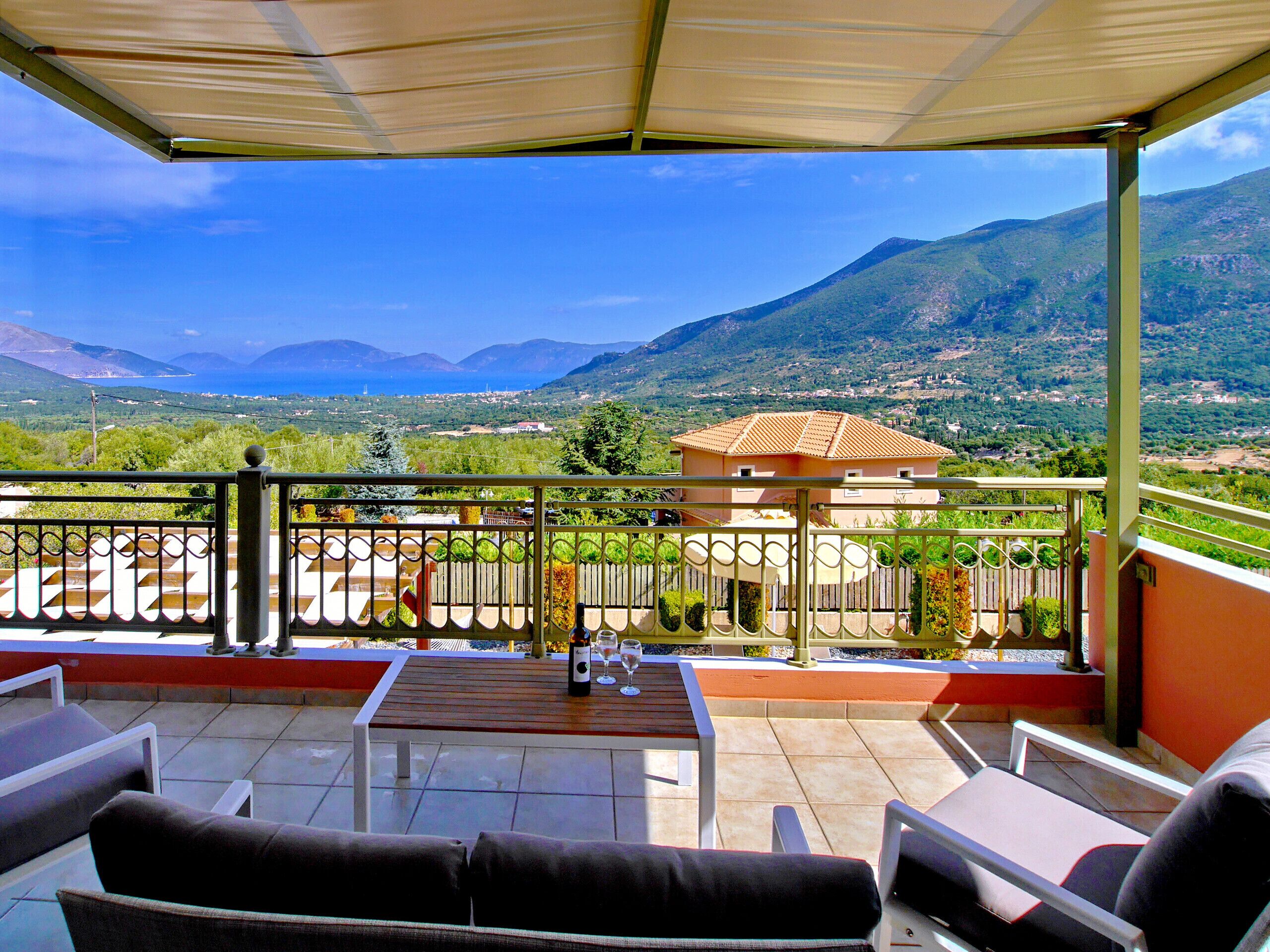 A terrace with outdoor furniture, a table, and a bottle of wine.