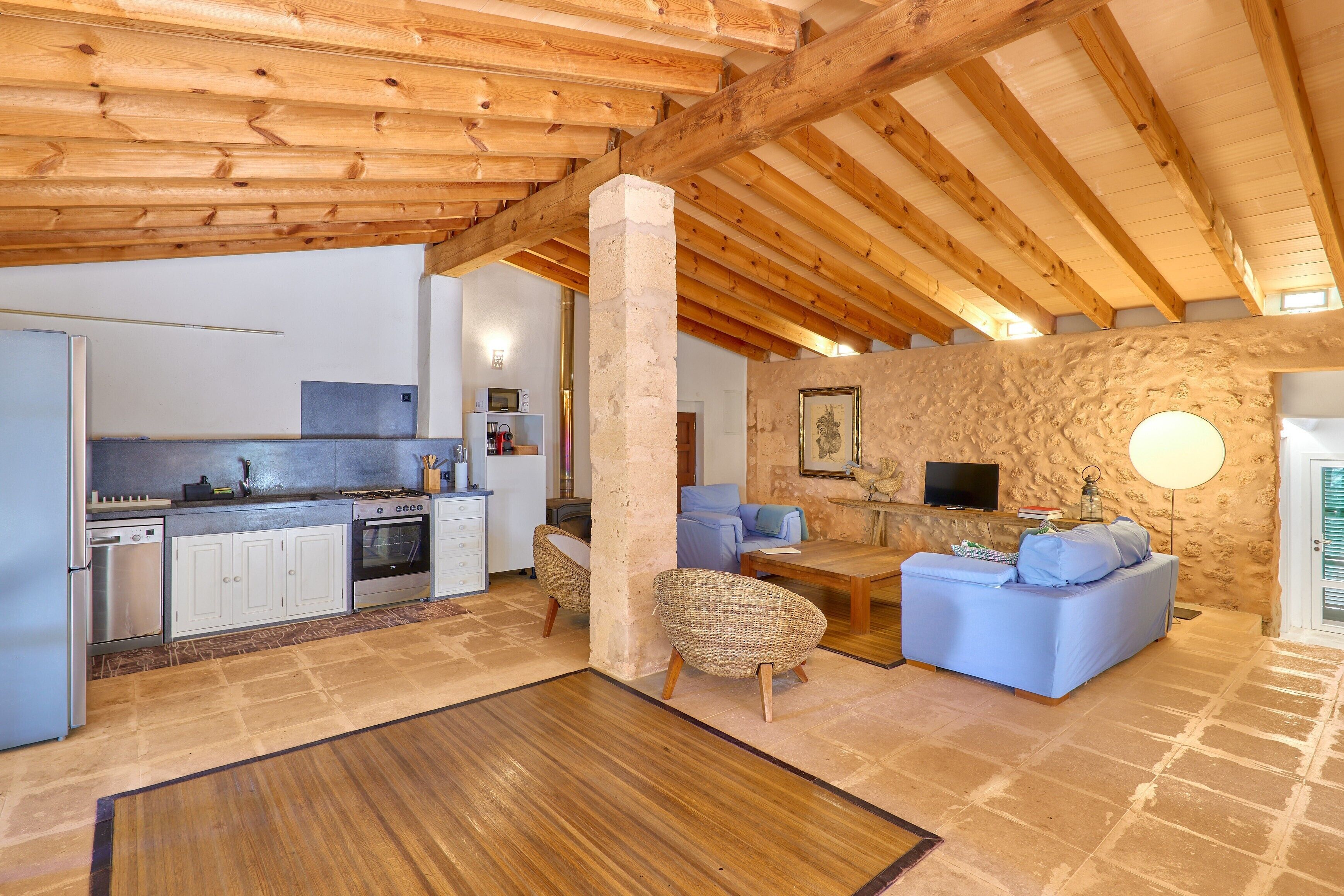 A spacious living area with a stone wall, a television, and a fireplace.