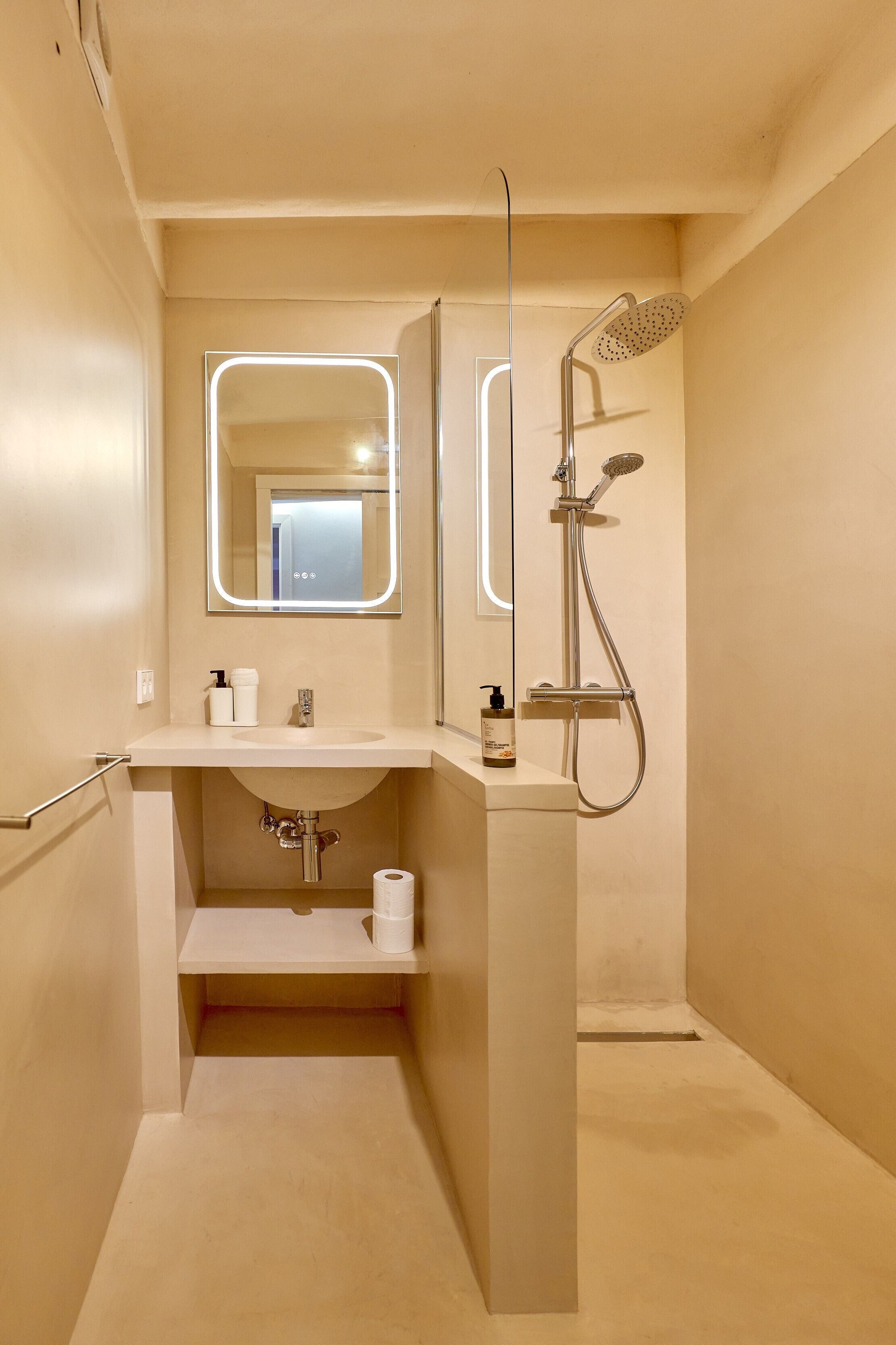 A compact bathroom with a sink, mirror, and shower.