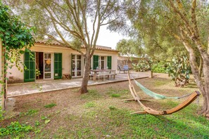 Une maison avec un patio, un hamac et un coin repas.