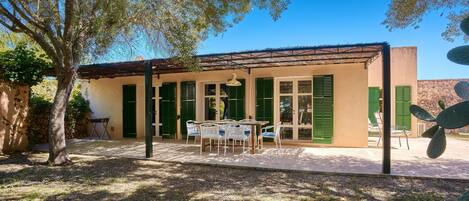 Un edificio con un patio, mobiliario exterior y una planta de cactus.