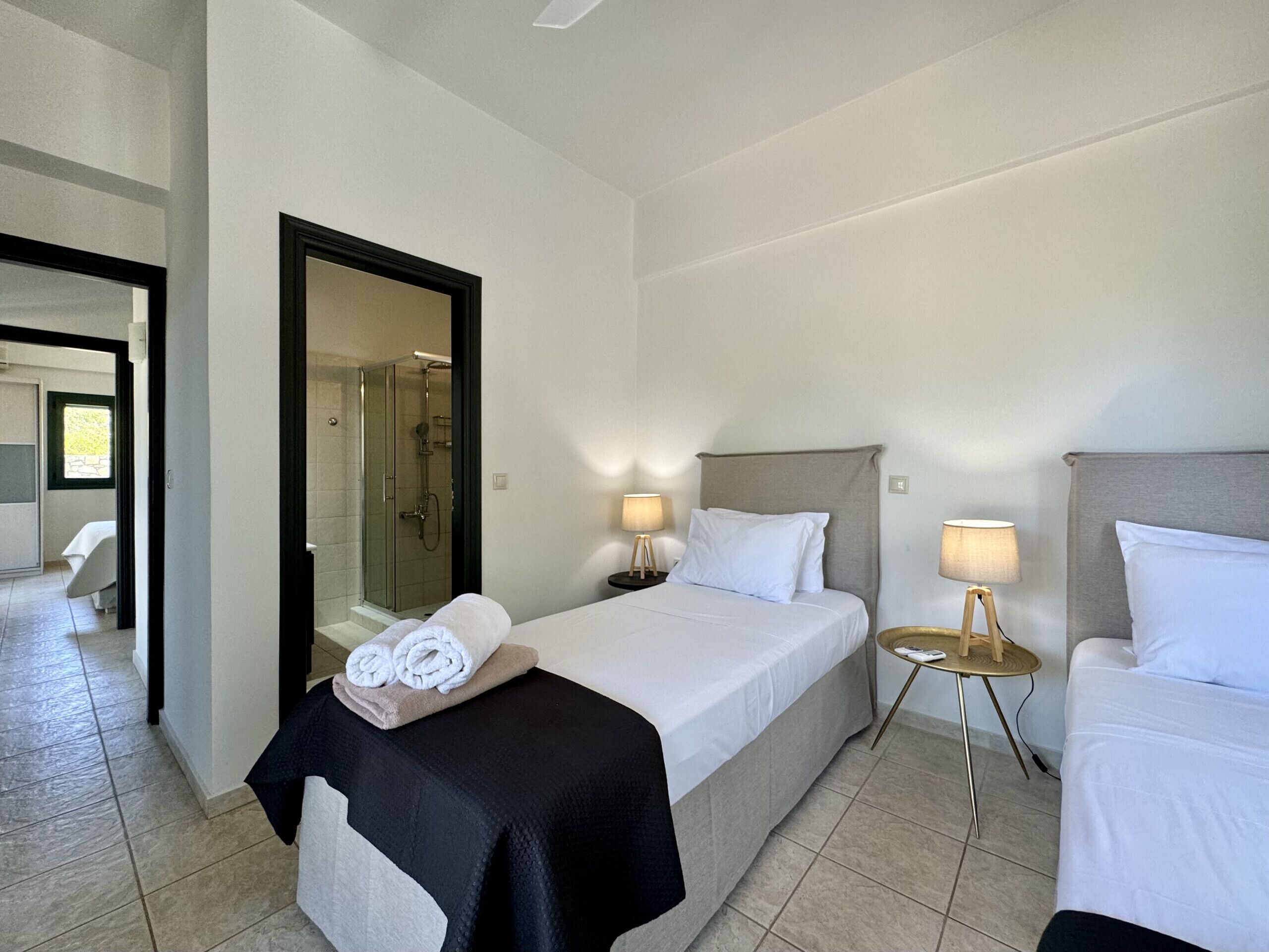 Ein Hotelzimmer mit Bett, Nachttisch mit Lampe, Badezimmer mit Dusche und Spiegel.