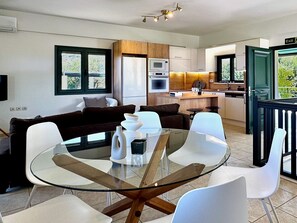 A modern kitchen with a dining area, a sofa, and a TV. - Villa Nynemia (Almyrida)