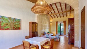 Un comedor con una mesa y sillas, un cuadro en la pared y una escalera que lleva a otra habitación.