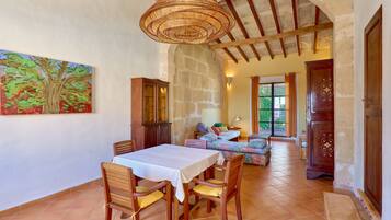Un comedor con una mesa y sillas, un cuadro en la pared y una escalera que lleva a otra habitación.