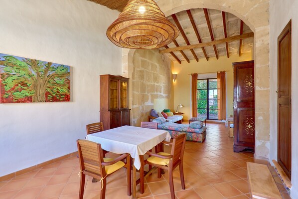Un coin repas avec une table et des chaises, un tableau accroché au mur et un escalier menant à une autre pièce.