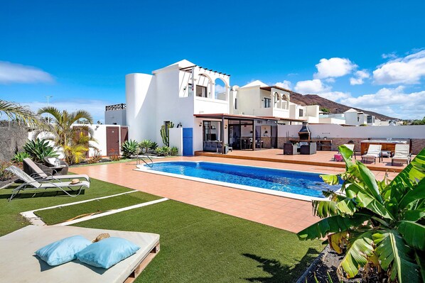Un área junto a la piscina con piscina, sillas de descanso y terraza amueblada.