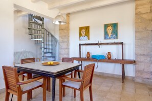 Un espace repas comprenant une table, des chaises, un escalier et des œuvres d’art accrochées au mur.