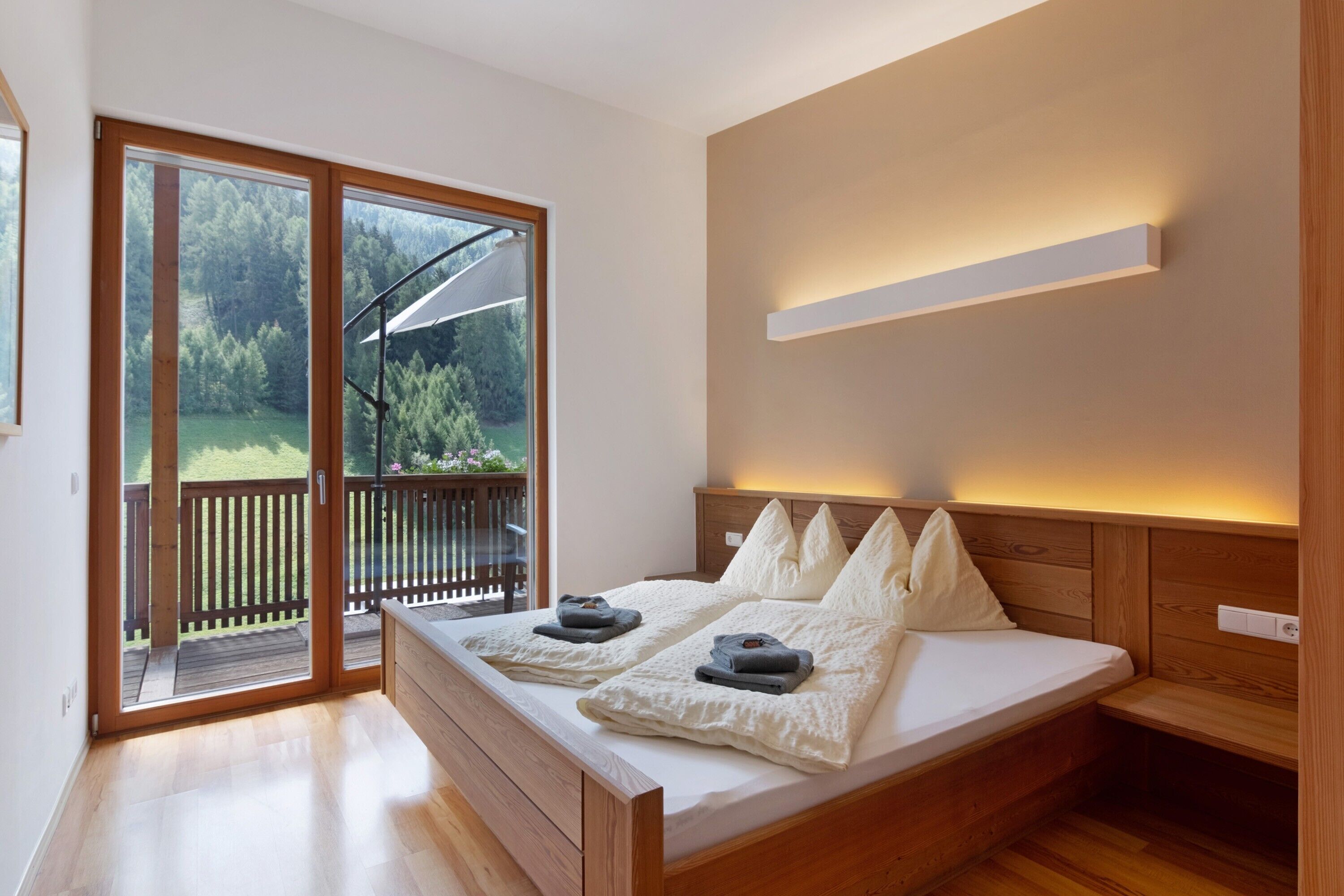 Une chambre avec un grand lit, une tête de lit en bois et une porte-fenêtre coulissante donnant sur un espace extérieur.