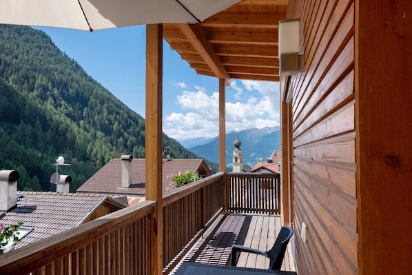 Un balcon en bois offrant une vue sur une chaîne de montagnes boisée.