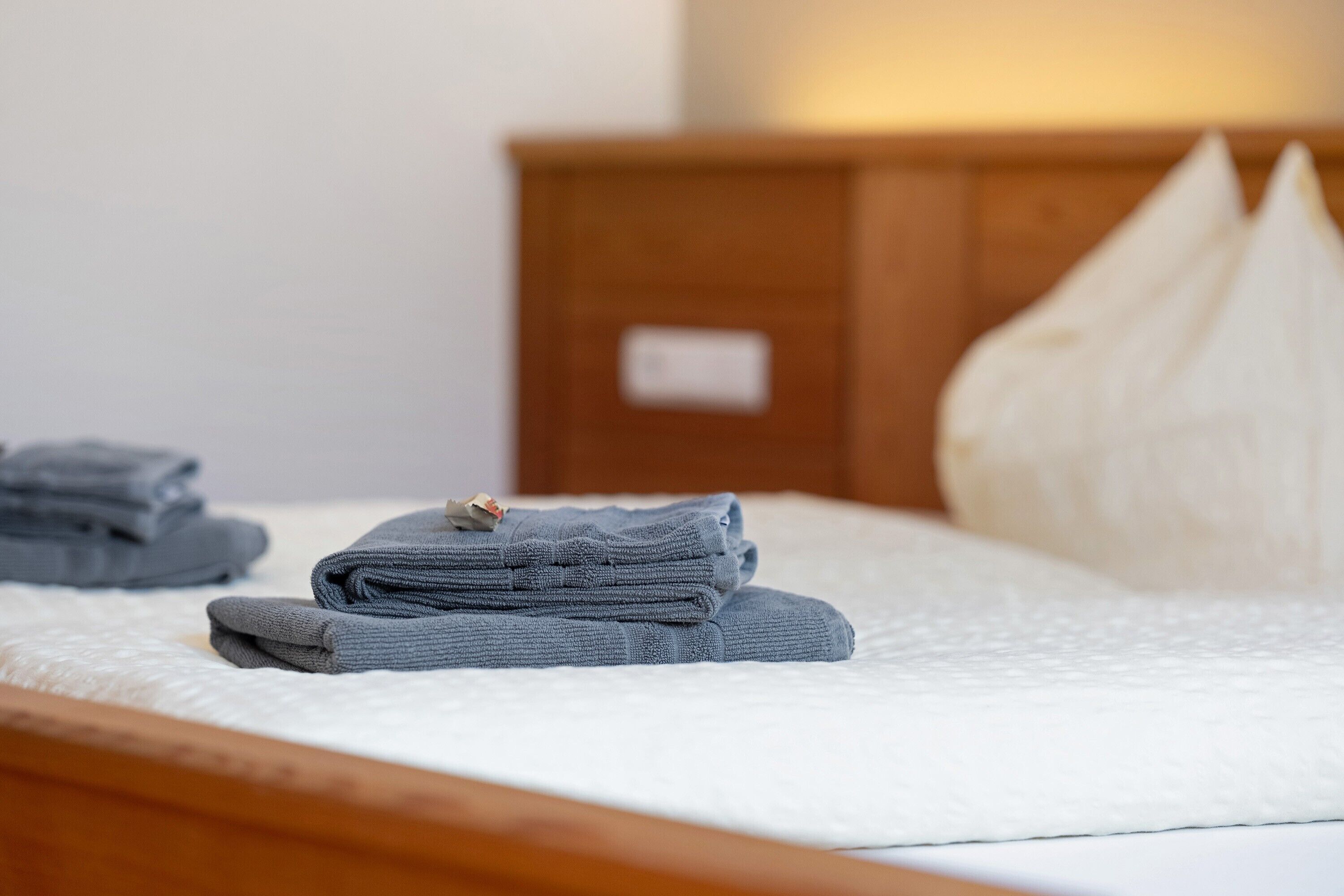 Een net opgemaakt bed met opgevouwen handdoeken en een kussen.