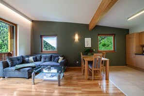 A modern living room with a sofa, glass coffee table, dining table with chairs, and wooden cabinets.