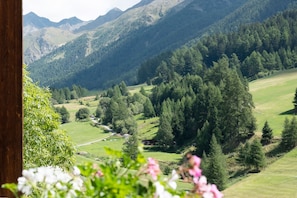 Paesaggio montuoso con una valle, una strada e un piccolo edificio.