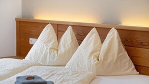 A bed with a wooden headboard and four white pillows. - Apartment “Pritscheshof Balkon” with Mountain View, Balcony & Terrace (Mals)