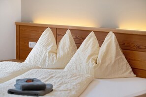 A bed with a wooden headboard and four white pillows.