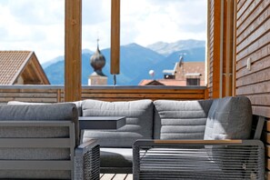 A modern outdoor seating area with a view of mountains and traditional buildings. - Charming Apartment “Ferienwohnung Terrasse” with Mountain View & Terrace; Parking Available (Mals)