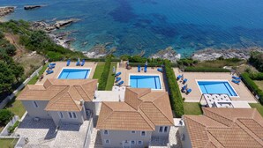 A coastal hotel with two swimming pools, terracotta roofs, and a view of the sea. - Villa Sakos (Skala)