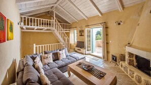 Un vaste salon doté d’un haut plafond, d’une cheminée intégrée, d’un grand canapé et d’un escalier menant à un niveau supérieur.