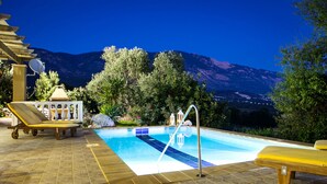 Una piscina con lettini e vista sulle montagne.