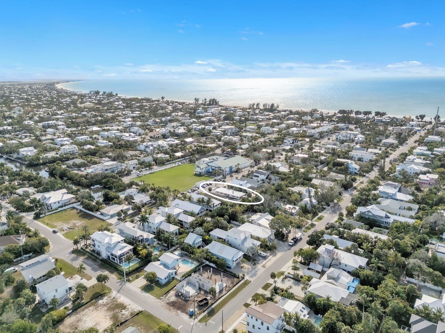 An aerial view of a coastal residential area with houses, a beach, and a clear sky.