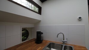 Una cocina con encimera de madera, un lavamanos de acero inoxidable y una ventana sobre el lavamanos.