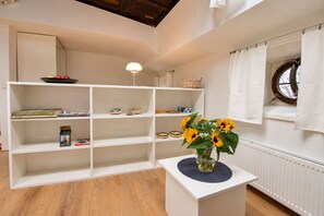 A room with a white bookshelf, a small table with a vase of sunflowers, and a window with a curtain.
