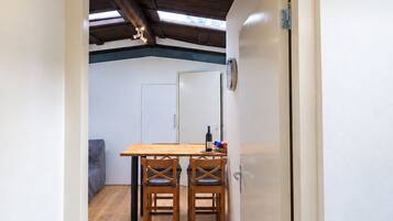 A room with a wooden dining table and chairs, a white door, and a view of a ceiling with exposed beams.