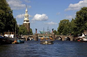 Un canal avec des bateaux, un pont et un beffroi.