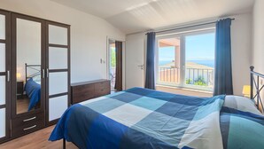 A bedroom with a large bed, a wardrobe with glass doors, and a balcony with a view. - Villa Pascal (Peruški)