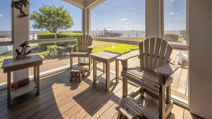 Eine überdachte Terrasse im Freien mit Holzsesseln und -tischen, mit Blick auf ein Gewässer und eine Anlegestelle.