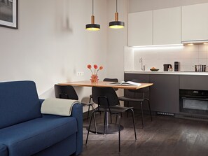 Een moderne keuken met witte kasten, een eettafel en een blauwe bank.