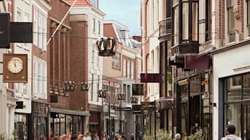 A pedestrian street lined with shops and buildings, featuring a clock and a bicycle.