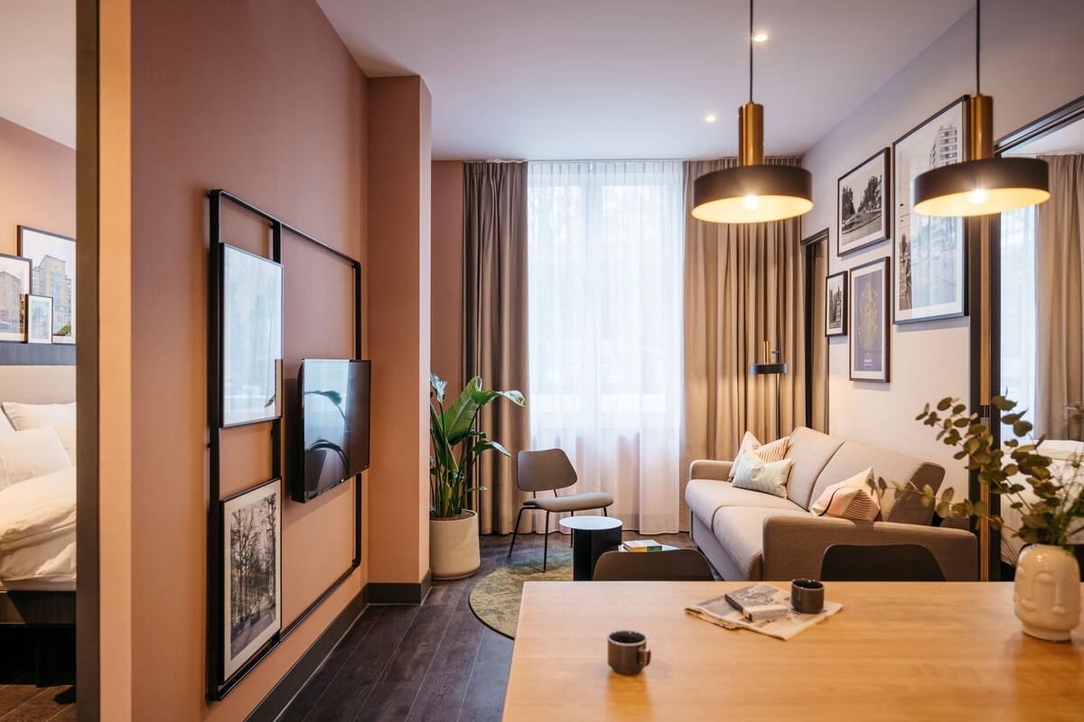 Une chambre d’hôtel moderne équipée d’un lit, d’un canapé, d’une table à manger et d’une grande fenêtre avec des rideaux.