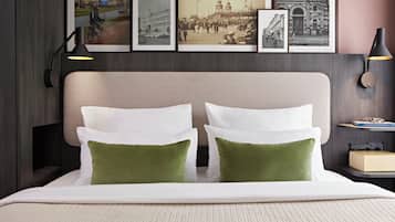 Een hotelkamer met een bed, foto's aan de muur en een nachtkastje met een lamp.