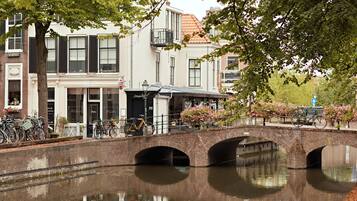 Een gracht met een bakstenen brug, gebouwen met luiken en fietsen.