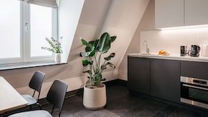 Een moderne keuken met donkere kastjes, een inbouwoven en een raam met een plant.
