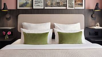 A neatly made bed with two pillows, a headboard, and a framed cityscape above.