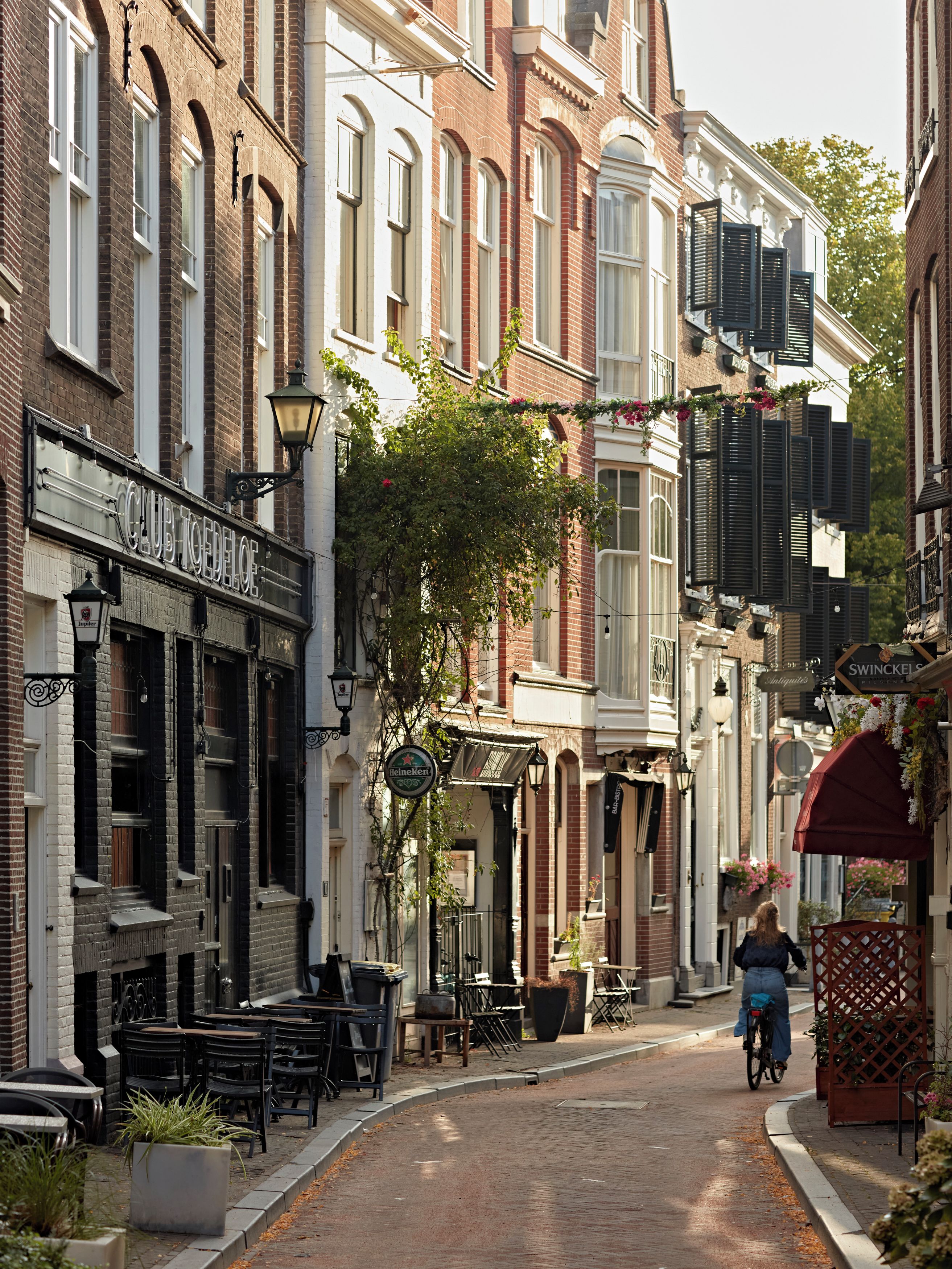 A street with buildings, a cyclist, and outdoor seating.
