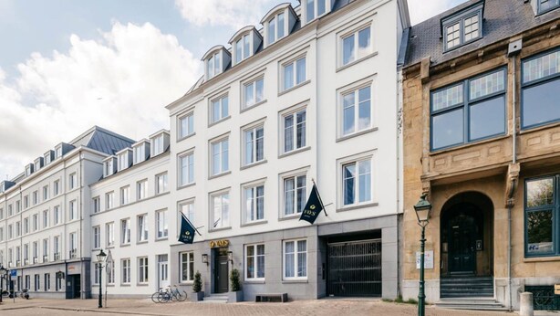Een hotel met meerdere verdiepingen, in klassieke Europese bouwstijl, met symmetrische ramen en een centraal gelegen ingang.