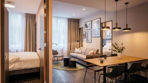 Een moderne hotelkamer met een bed, een bank, een eettafel, stoelen en een bijzettafeltje.