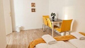 A hotel room with a bed, a table with chairs, a potted plant, and a trash bin. - Modern Apartment in The Heart of Vienna 9 (Vienna)